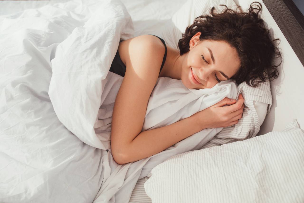 young woman lying in bed and keeping eyes closed